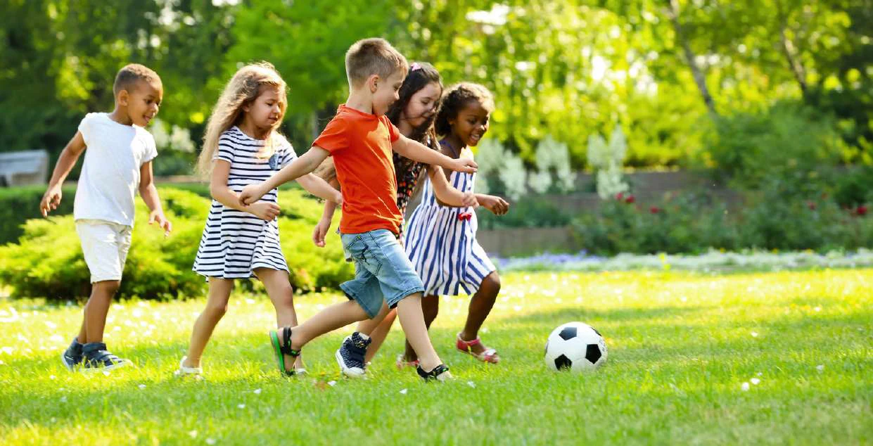 Crianças a brincar com uma bola num jardim
