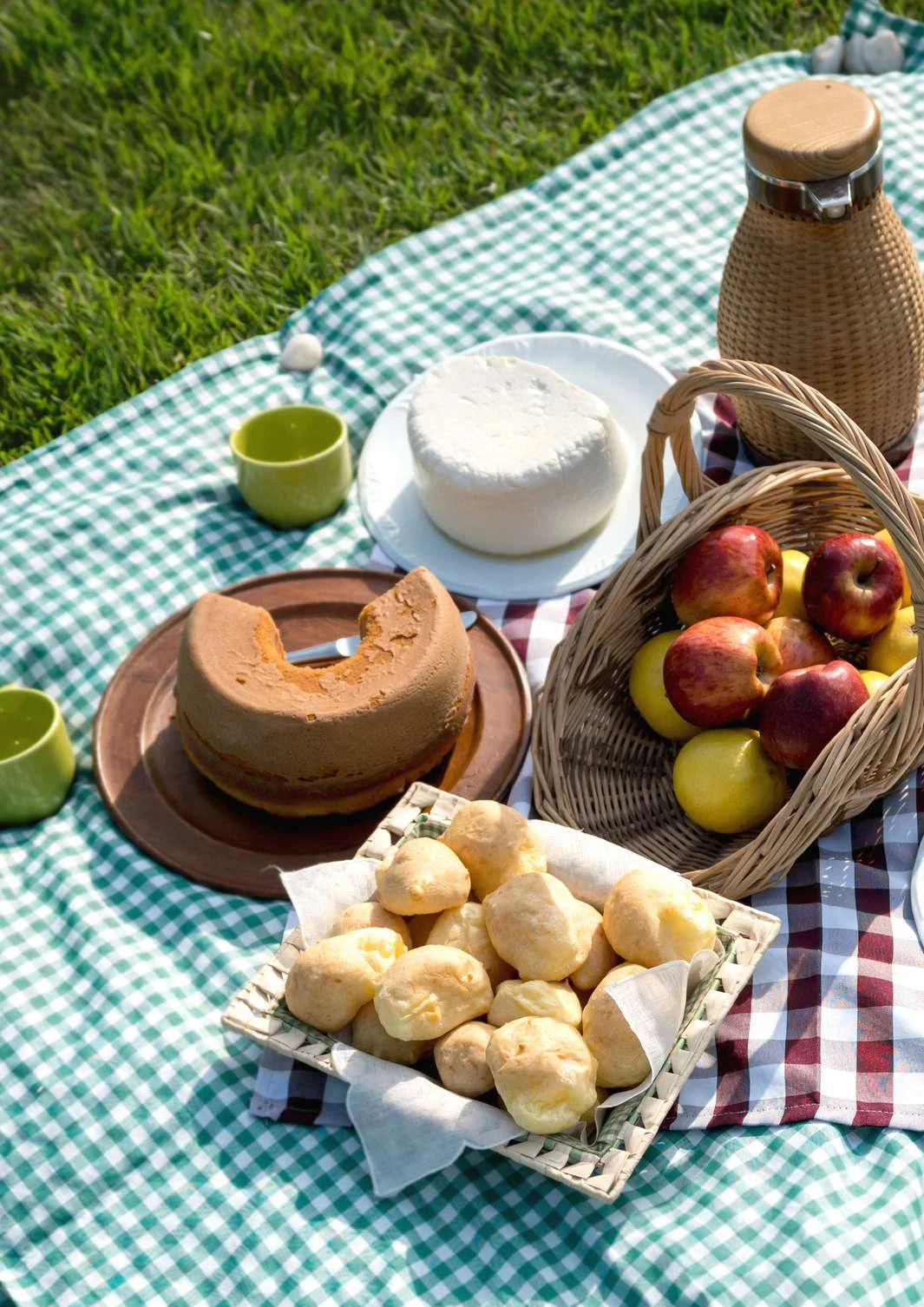 Toalha de piquenique na relva com fruta, pão e cestos
